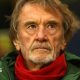 Sir Jim Ratcliffe in a green coat and red scarf