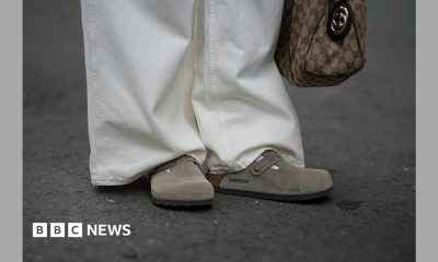 A person is seen wearing cream-white wide-leg jeans with subtle stripes and Boston clogs in soft suede with an open back and adjustable strap from Birkenstock.