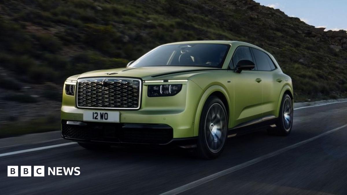 A green Bentley SUV is driven along a road with a hill behind it.