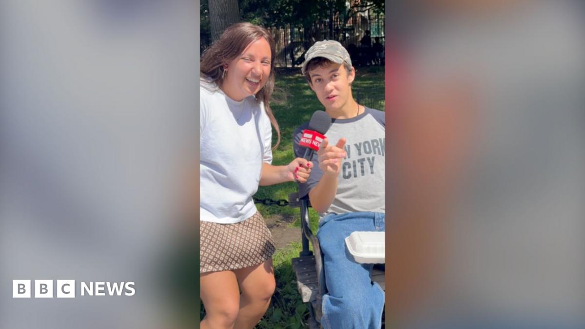 Yasmin Rufo smiles while a young man points at the camera wearing jeans and a New York City T-shirt.