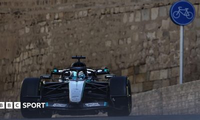 Mercedes' George Russell crests a hill during Azerbaijan Grand Prix second practice. In the background can be seen the walls of a castle and a cycling road sign