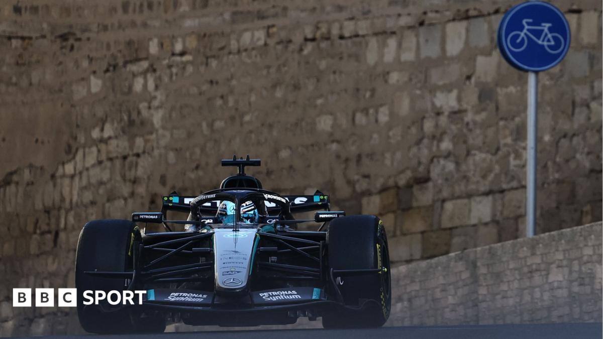 Mercedes' George Russell crests a hill during Azerbaijan Grand Prix second practice. In the background can be seen the walls of a castle and a cycling road sign