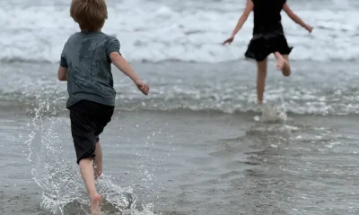 The author’s children run to the ocean while she photographs them.