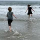 The author’s children run to the ocean while she photographs them.