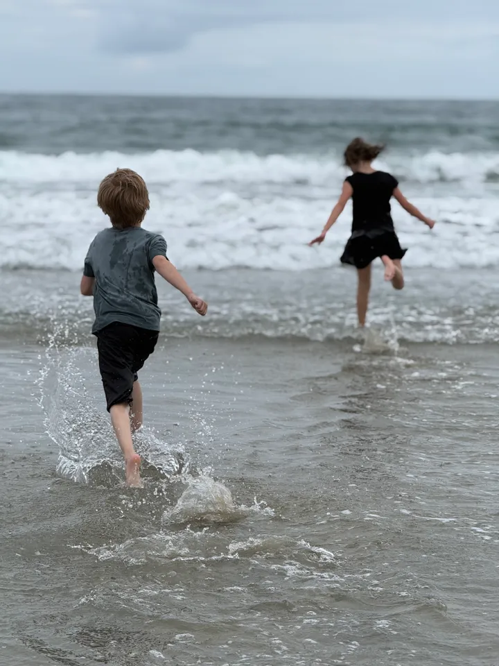 The author’s children run to the ocean while she photographs them.