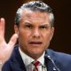 Pete Hegseth gestures by lifting his hand as he frowns