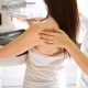 A generic picture of a woman having a mammogram. She is in front of a machine with another woman helping her.