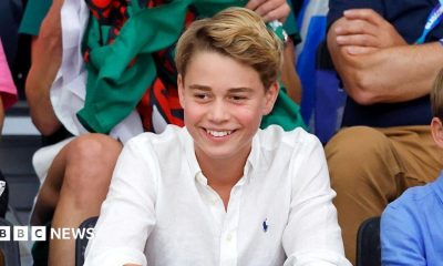 Prince George at the Commonwealth Games in August 2026. He is wearing a white shirt and smiling.