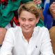 Prince George at the Commonwealth Games in August 2026. He is wearing a white shirt and smiling.