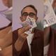 A man with glasses holds a bunch of bank notes in front of his face.
