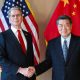 US Treasury Secretary Scott Bessent shakes the hand of China's top trade negotiator He Lifeng stand in front of both countries' flags.