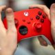 A close up of someone's hands holding a red Xbox controller