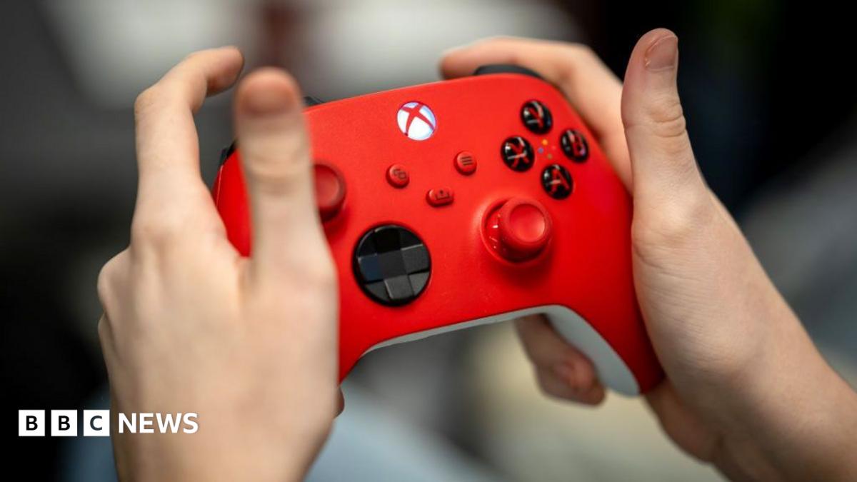 A close up of someone's hands holding a red Xbox controller