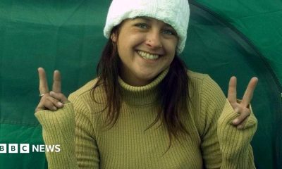 A woman smiles into the camera making peace signs with both hands
