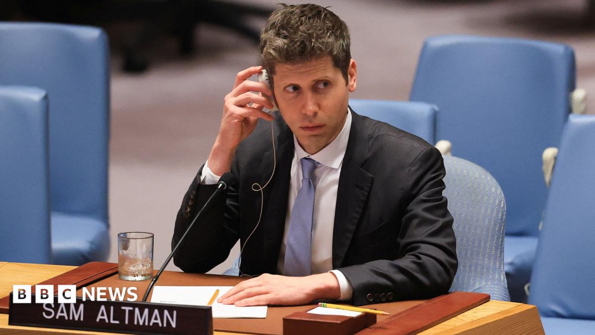 Sam Altman of OpenAI sitting before the US Security Council wearing a suit and tie while listening to a translation of comments.