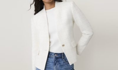 A woman wearing a white blazer, white top, and blue jeans