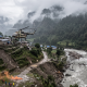 A rescue helicopter flying low over a flood-damaged mountain village in Nepal