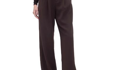 A woman wearing black flats, a black top, and dark brown pants