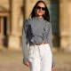 Alba Garavito Torre wears white pearl earrings, a gingham checkered black and white shirt with Long Sleeve Ruffles from Serendipia, Mom jeans in white from Maison 123 Paris, a brown thin leather belt, on October 10, 2021 in Paris, France.