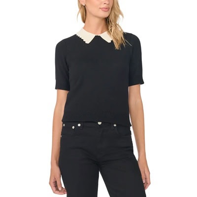 A woman wearing black pants and a black sweater with ivory scalloped trim at the neckline