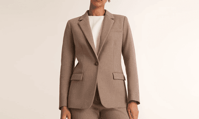 A woman wearing a white top and a dark tan suit