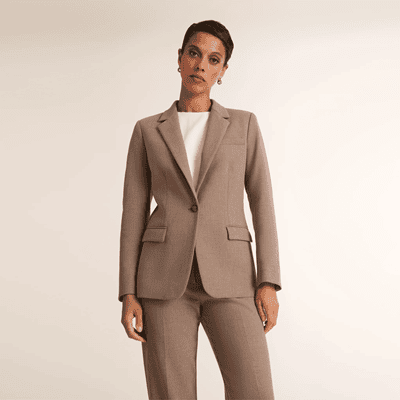 A woman wearing a white top and a dark tan suit