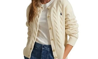 A woman wearing a white top, cream cable cardigan, and blue jeans