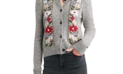 A woman wearing a gray cardigan with red and white flowers, with gray jeans