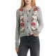 A woman wearing a gray cardigan with red and white flowers, with gray jeans