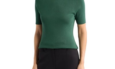 A woman wearing a green short-sleeved sweater and black pants