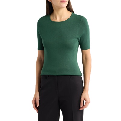 A woman wearing a green short-sleeved sweater and black pants