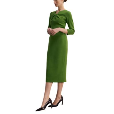A woman wearing a green dress and black pumps