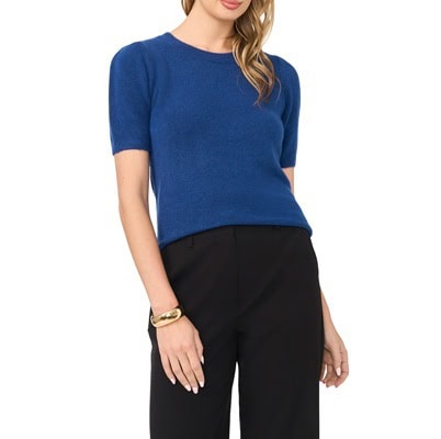 A woman wearing a medium blue short-sleeved sweater and black pants