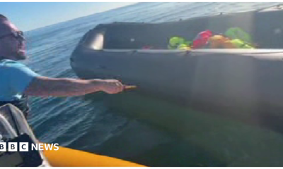 Anti-migrant campaigner leaning out of a boat appearing to hold a knife and to be shouting