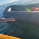 Anti-migrant campaigner leaning out of a boat appearing to hold a knife and to be shouting