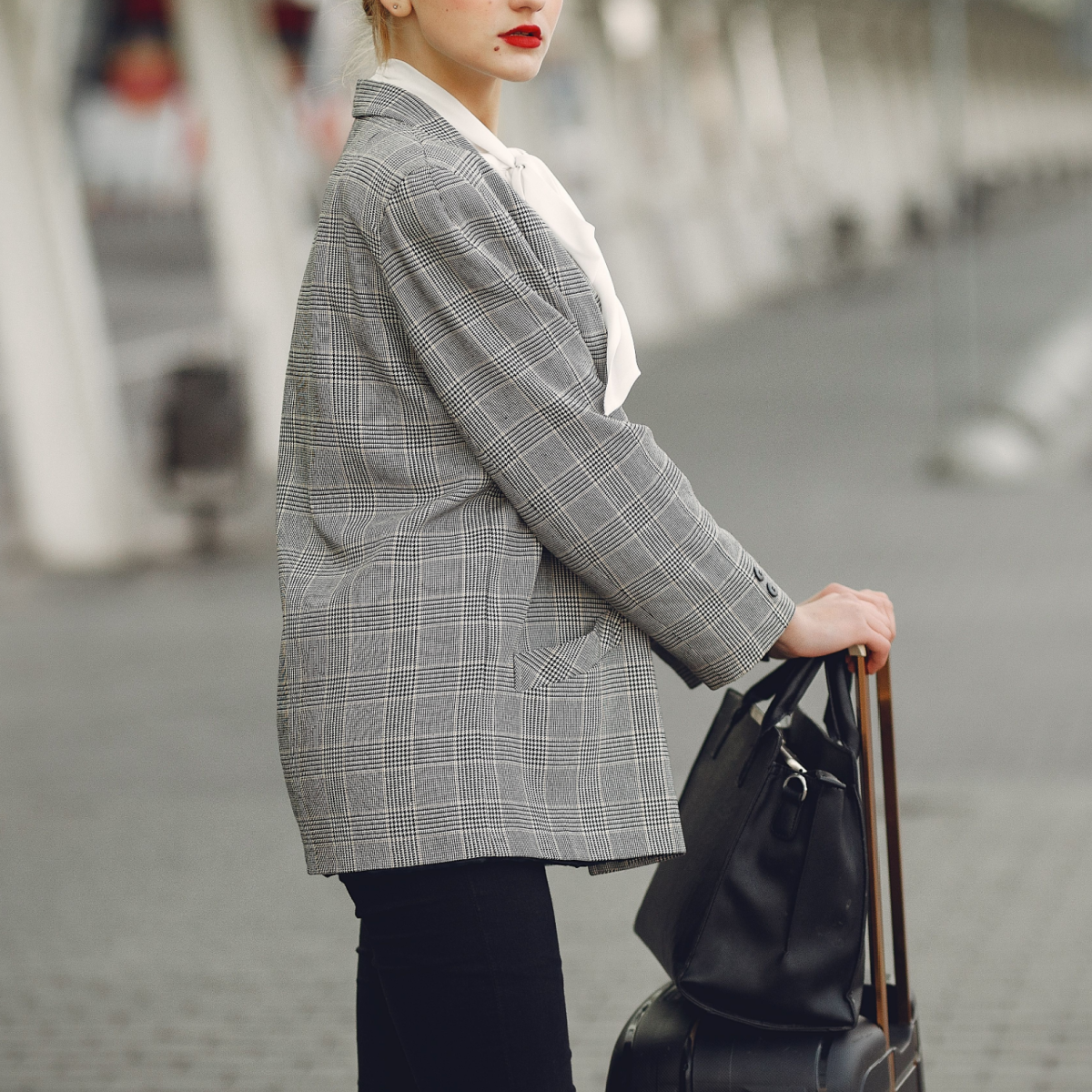 annoyed professional woman stands outside airport with her luggage
