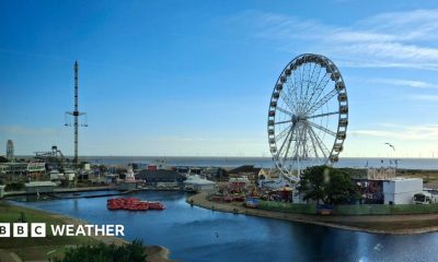 A seaside scene in Skegness with a big wheel and a funfair, the skies are blue