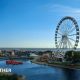 A seaside scene in Skegness with a big wheel and a funfair, the skies are blue