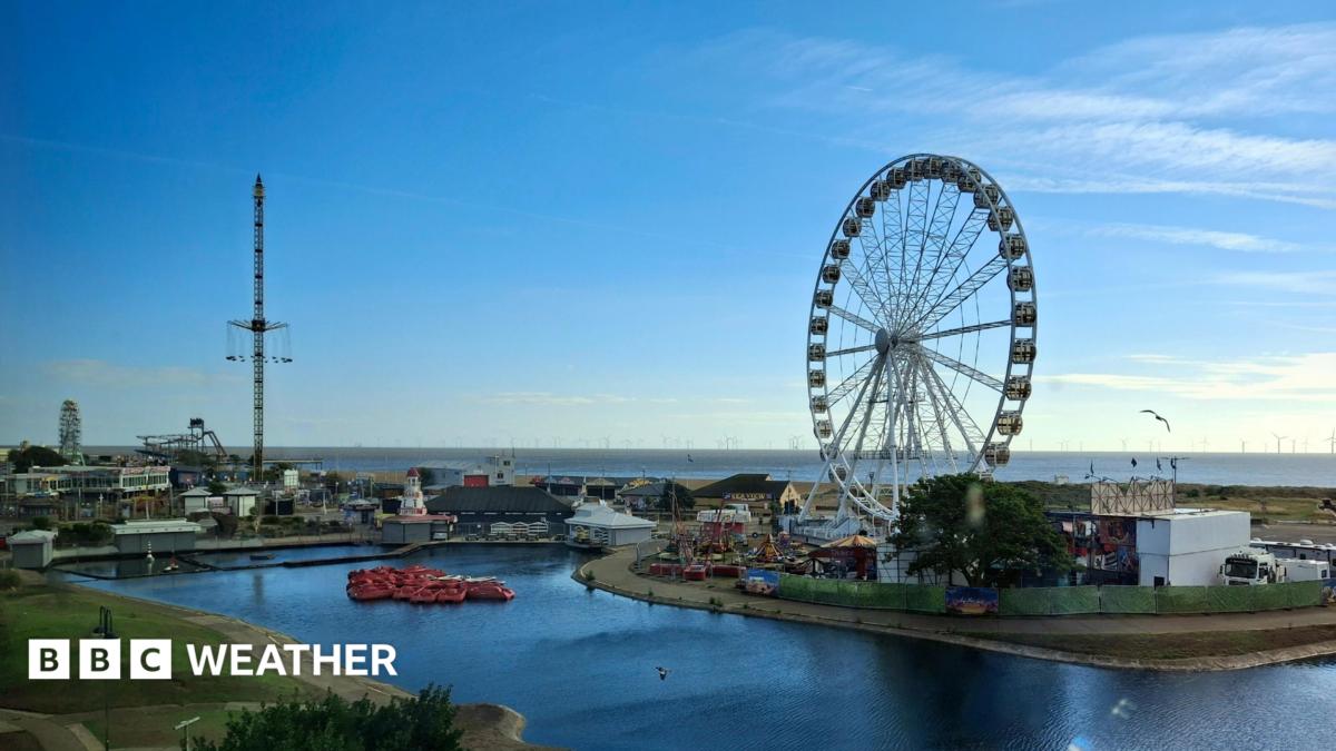 A seaside scene in Skegness with a big wheel and a funfair, the skies are blue