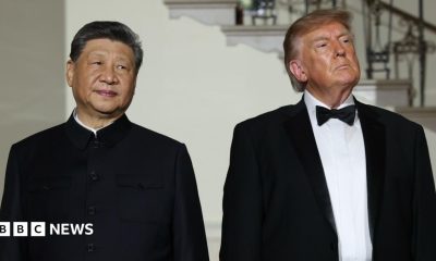 Xi Jinping and Donald Trump standing next to each other looking pensive, they are both wearing suits