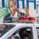 Police drive past a wall painted with the image of killed Haitian President Jovenel Moise