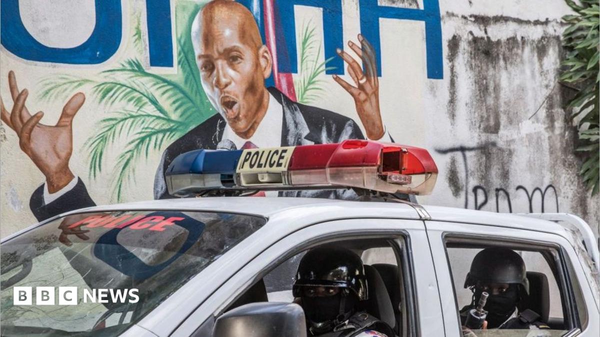 Police drive past a wall painted with the image of killed Haitian President Jovenel Moise