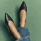 woman wears black pointy toed flats and blue jeans