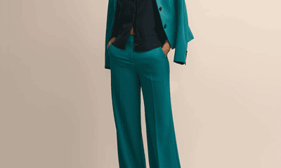 polished Black woman wears teal green suit; the suit jacket is just laid over her shoulders