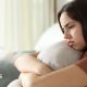 Disappointed looking young woman hugs a cushion.