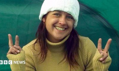 A woman smiles into the camera making peace signs with both hands