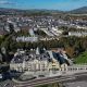 An aerial view of Douglas from the promenade on a bright day, showing hundreds of buildings with areas of trees breaking it up.