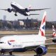 Three British Airways aircraft at Heathrow Airport, one is taking off in the distance with London skyline in the background
