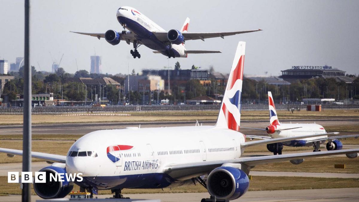 Three British Airways aircraft at Heathrow Airport, one is taking off in the distance with London skyline in the background