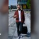 Consumer expert Harry Kind is walking, pulling a suitcase with his left hand. He's wearing a red jacket over a white t-shirt.